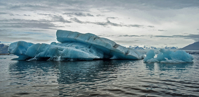 A imagem mostra uma geleira no meio do mar. Ela está derretendo devido ao aquecimento global.