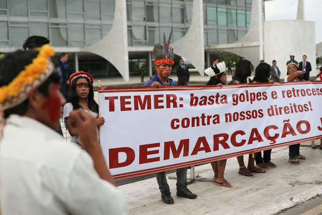 Foto de índios na frente do palácio do planalto segurando uma faixa que diz: Temer, basta golpe e retrocesso contra nossos direitos. Demarcação Já!