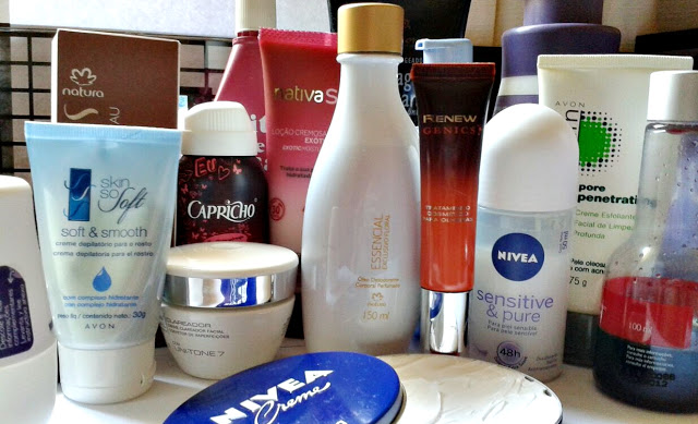 Vários recipientes de cosméticos distribuídos em toda a foto. Desde hidratantes a desodorantes e óleos. À frente um pote redondo aberto, deixando aparecer o conteúdo de dentro.