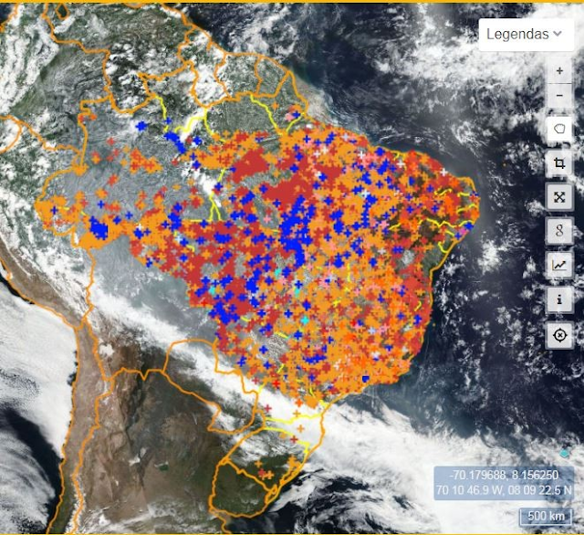 A imagem mostra uma visão de satélite. Mostra a América do Sul, tendo o Brasil sido contornado. No Brasil tem vários pontinhos azuis, vermelhos e laranjas espalhados que indicam focos de queimadas. A maioria dos focos estão na região Nordeste, Norte e Centro-Oeste.